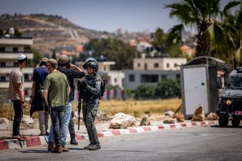 Israeli Border Police officer argues with Jewish teenage settlers at the entrance to the West Bank village of Turmus Aya.