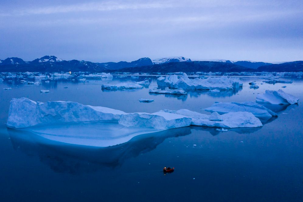 A boat navigates at night next to large icebergs near the town of Kulusuk, in eastern Greenland.