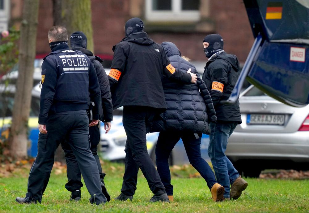 A suspect is escorted by police officers for questioning in Karlsruhe, Germany, on December 7, 2022.