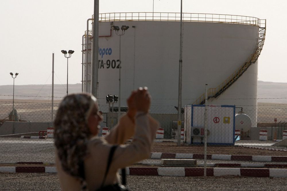 An Iraqi woman takes a photograph at an oil refinery near the village of Taq Taq, in the autonomous Iraqi region of Kurdistan, on May 31, 2009.