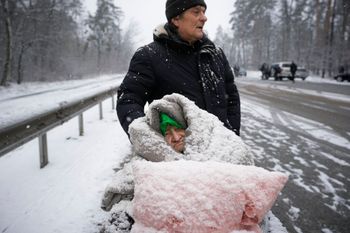 An elderly woman is coated in snow as she sits in a wheelchair after being evacuated from Irpin, on the outskirts of Kyiv, Ukraine, on March 8, 2022.