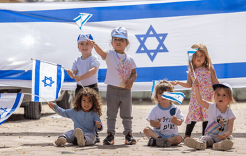 Des enfants jouent avec des drapeaux israéliens avant le 75e jour de l'indépendance d'Israël au Moshav Yashresh, le 19 avril 2023.