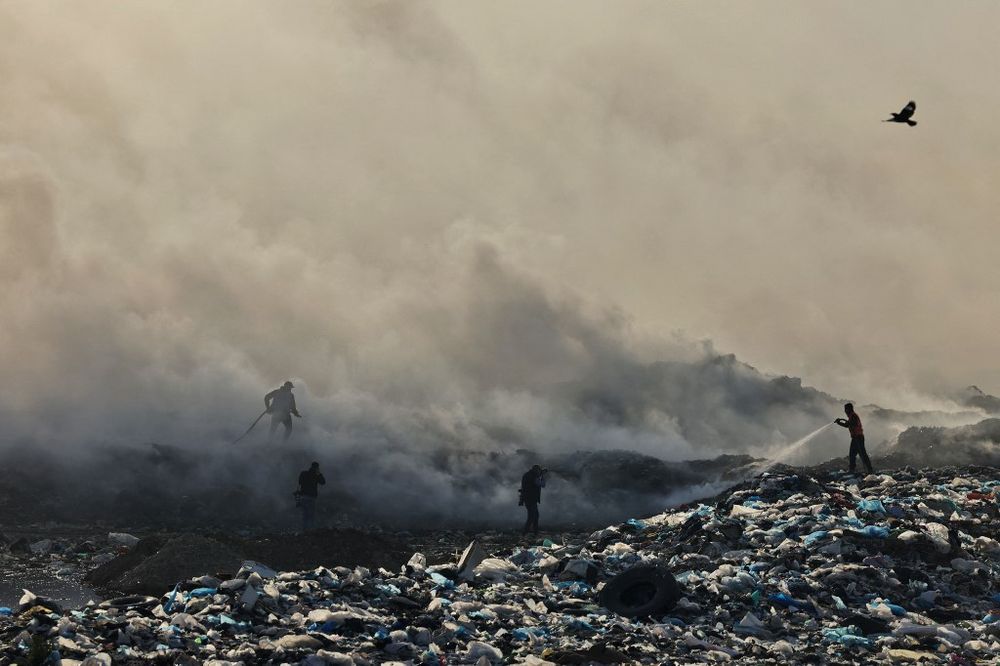 Palestinian civil defense men extinguish a fire in a waste dump, east of Gaza City.