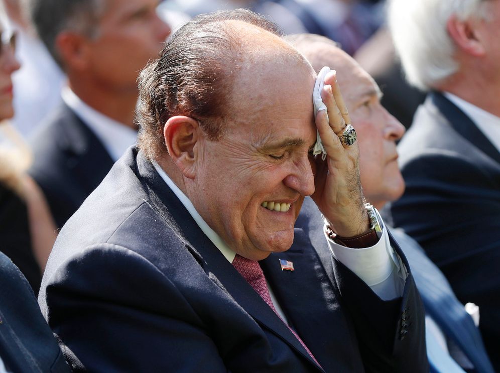 In this July 29, 2019 file photo, Rudy Giuliani, an attorney for President Donald Trump, left, wipes his forehead as he listens to President Donald Trump speak in the Rose Garden of the White House in Washington.