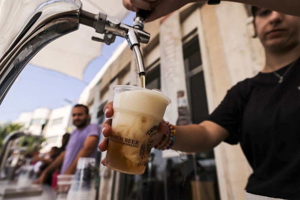 A bartender serves visitors on September 2, 2022, during the annual annual Oktoberfest beer festival in the village of Taybeh, east of the West Bank city of Ramallah.