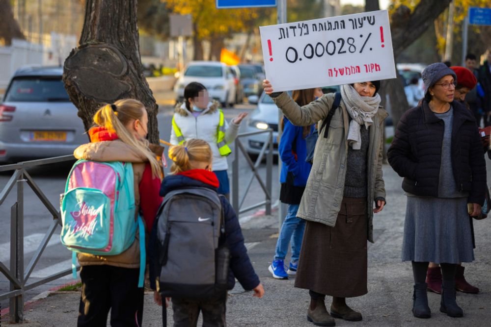 Anti-Covid vaccine activists protest outside a school as children go to class in Jerusalem, on December 29, 2021.