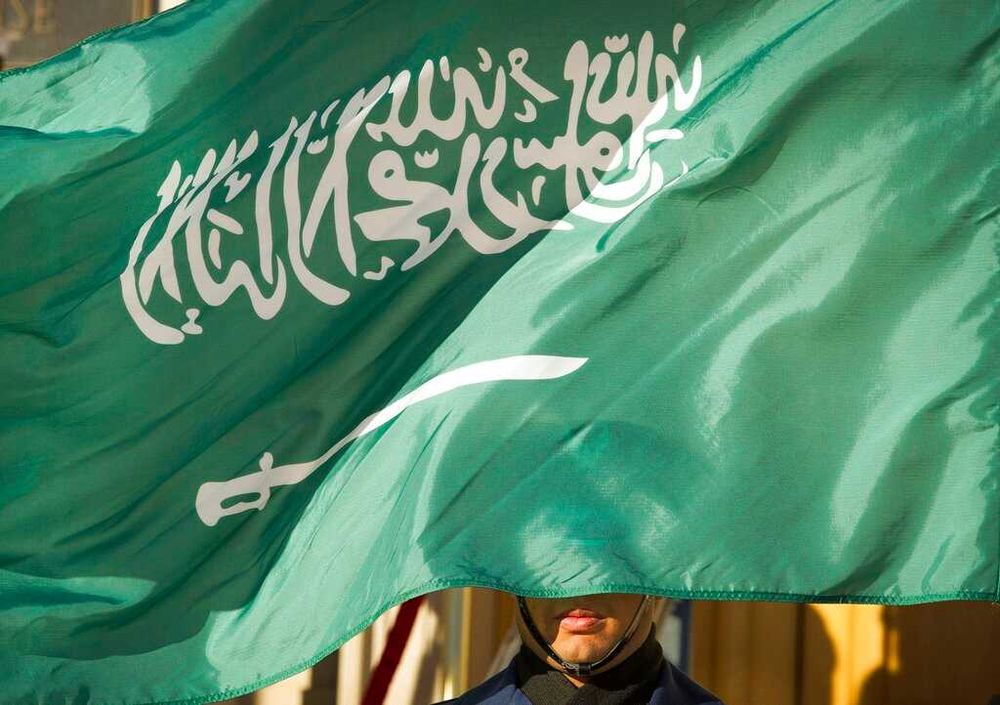 An honor guard member is covered by the flag of Saudi Arabia in Washington, the United States.