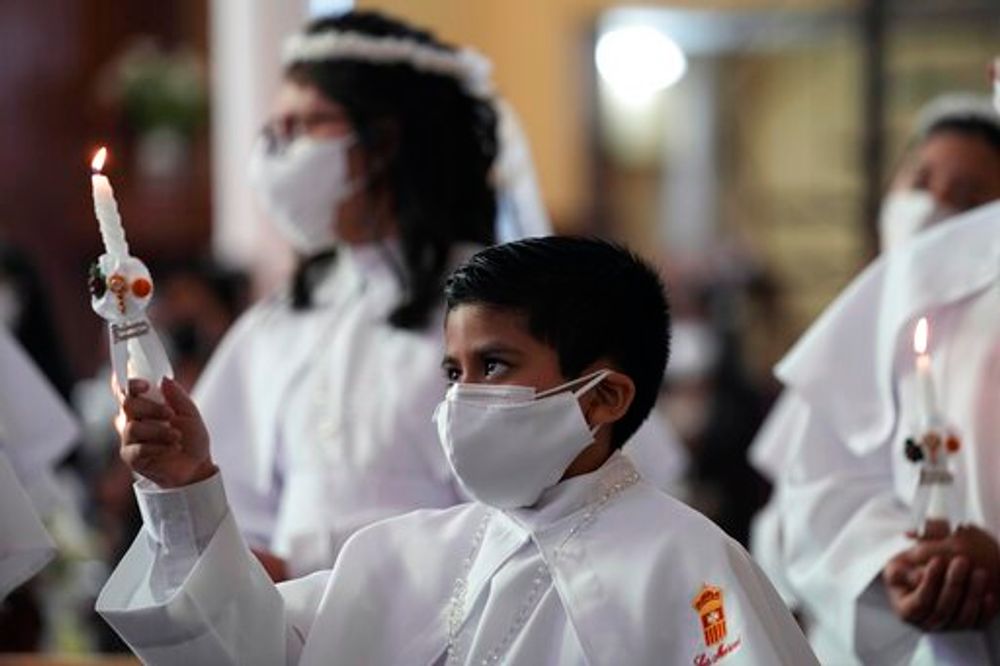 A boy wearing a protective face mask holds a candle at the Nuestra Senora de la Merced Catholic church in Lima, Peru, December 3, 2021.