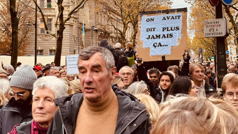 A banner reading 'We were saying Never Again...' at the Paris march
