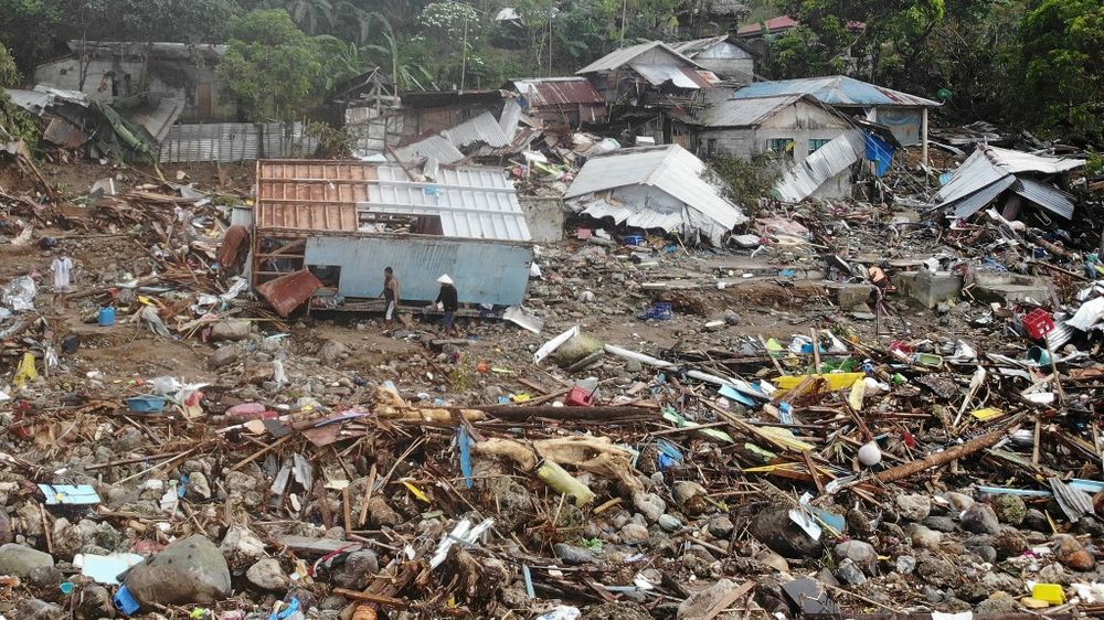 An aerial view shows residents walking past destroyed houses in the village of Pilar, Abuyog town, Leyte province, in the Philippines on April 14, 2022.