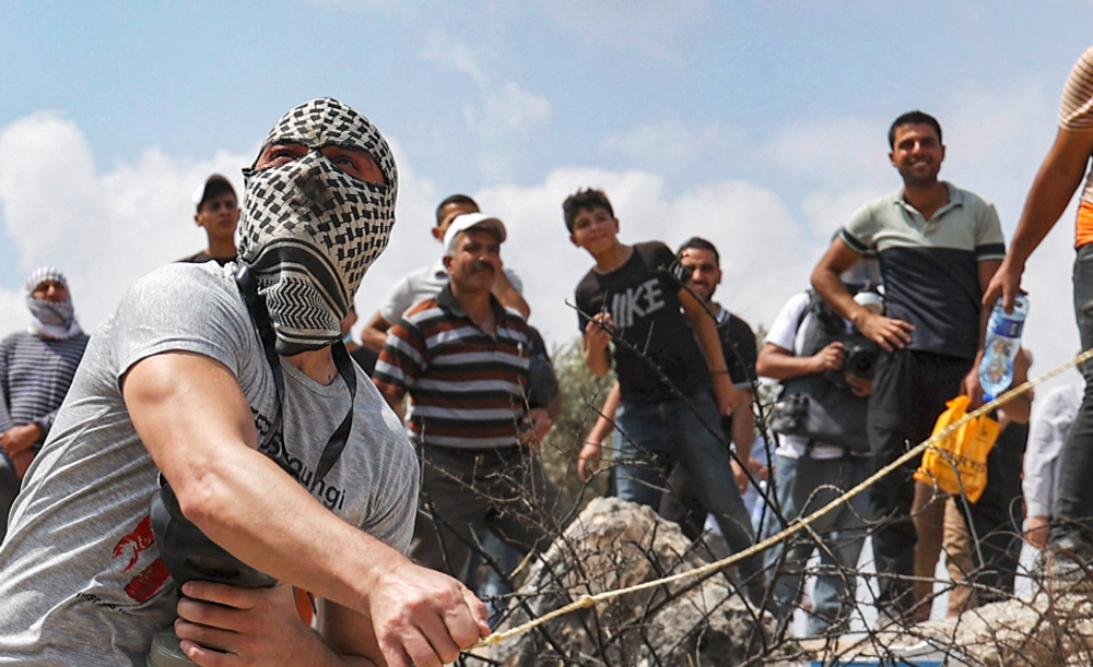 Un manifestant palestinien utilise une fronde pour lancer des pierres sur les forces israéliennes lors d'affrontements dans la ville de Beita, près de Naplouse, en Cisjordanie