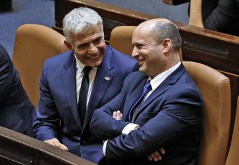 Israel's Alternate Prime Minister and Foreign Minister Yair Lapid (L) converses with Prime Minister Naftali Bennett in Israel's parliament in Jerusalem, on June 13, 2021