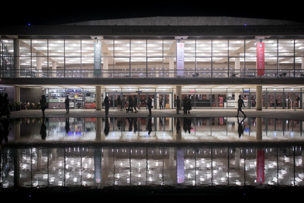 People reflected in a water fountain in front of the concert hall Charles Bronfman Auditorium, at HaBima square in Tel Aviv, Israel.
