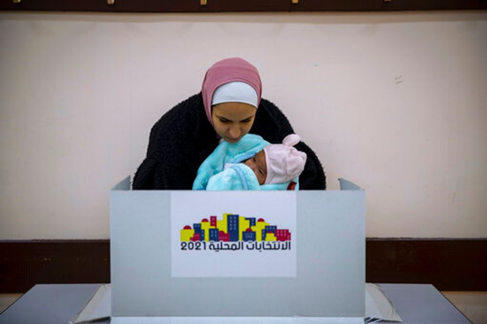 A Palestinian woman casts her vote at a polling station during municipal elections in the West Bank village of Kifl Haris, December 11, 2021.
