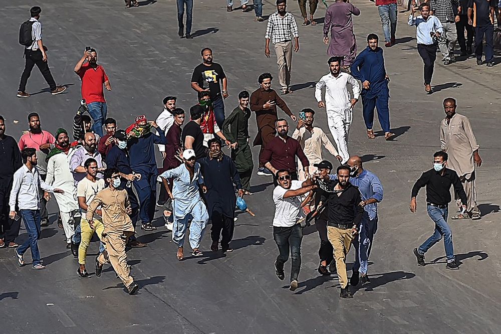 Pakistan Tehreek-e-Insaf party activists and supporters of former Pakistan's Prime Minister Imran hold a policeman (front 3R) during a protest against the arrest of their leader in Karachi