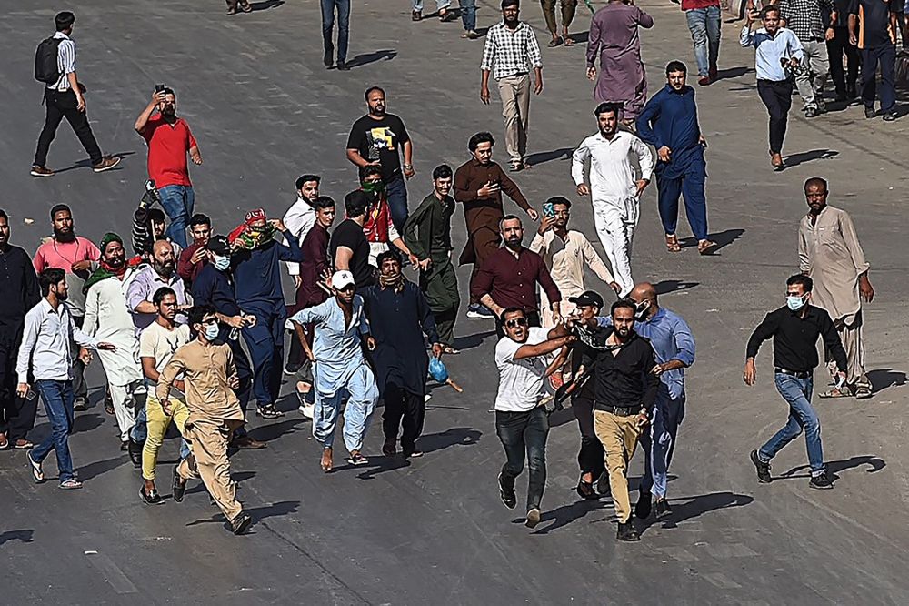 Pakistan Tehreek-e-Insaf party activists and supporters of former Pakistan's Prime Minister Imran hold a policeman (front 3R) during a protest against the arrest of their leader in Karachi