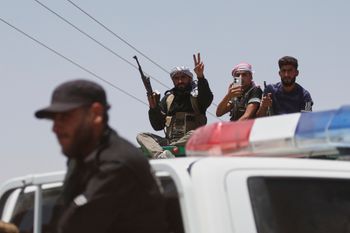 قوات الأمن الحكومية السورية، في المقدمة، تمنع مقاتلين بدو، في الخلفية، من دخول محافظة السويداء، في قرية بصر الحرير، جنوب سوريا، الأحد 20 يوليو/تموز 2025. 