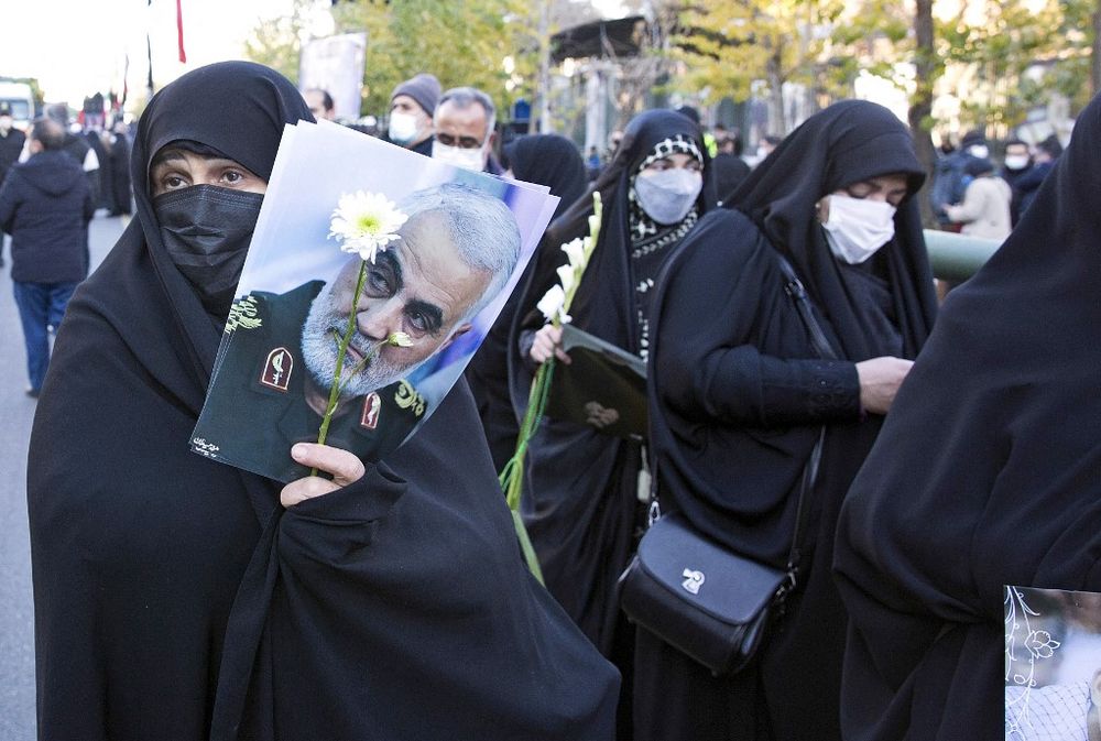 Iranian mourners hold a picture of slain commander Qasem Soleimani in Tehran, Iran, on January 6, 2022.