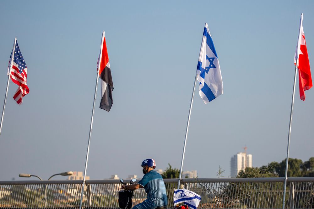 A man rides past the flags, from left, of the United States, United Arab Emirates, Israel and Bahrain at the Peace Bridge in Netanya, Israel, on September 14, 2020.