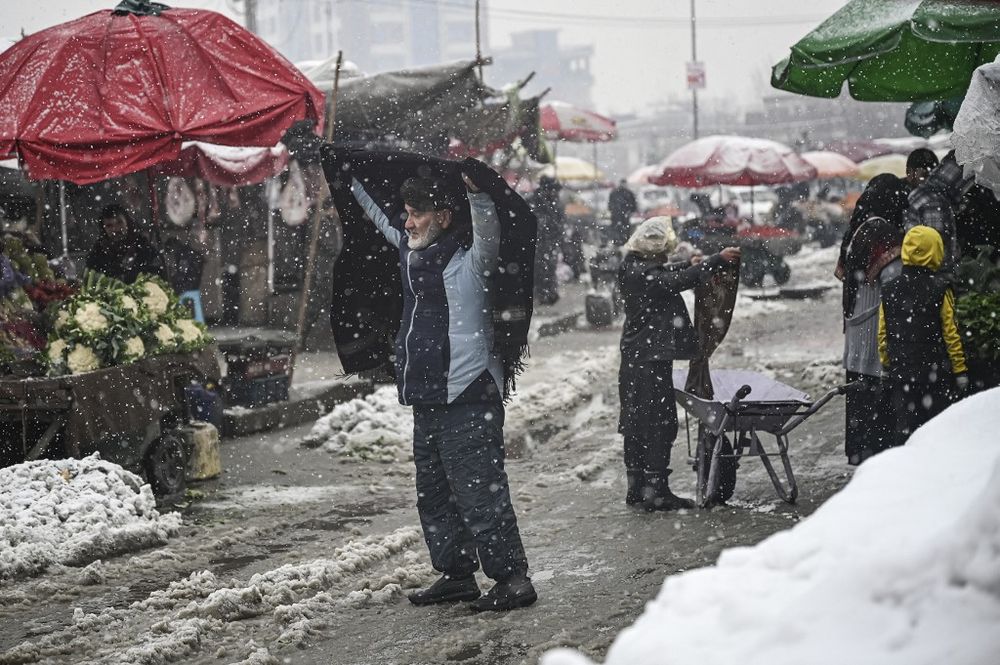 A man covers himself with a shawl during heavy snowfall at a market in Kabul, Afghanistan, on January 4, 2022.