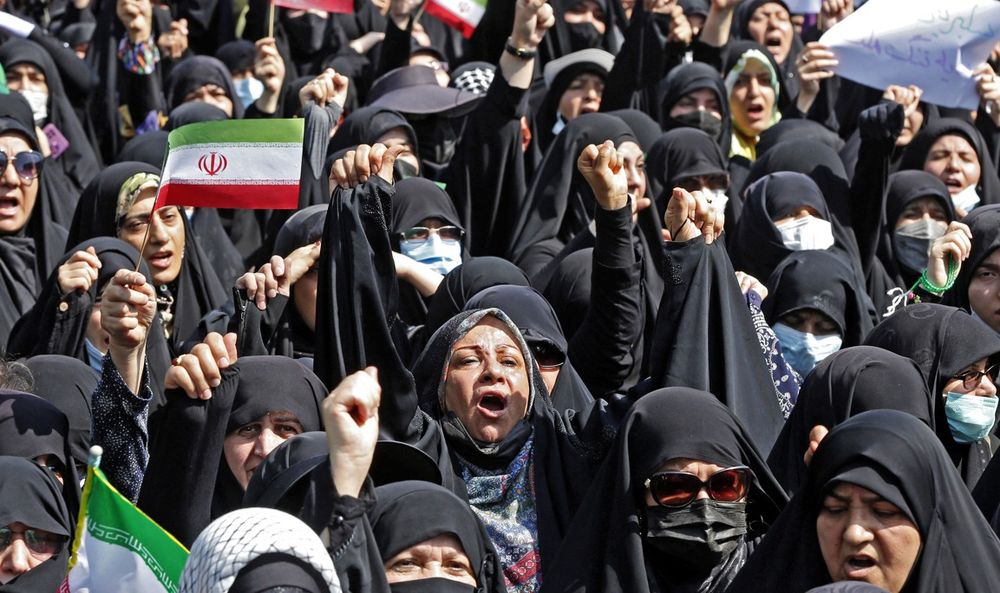 Des Iraniens brandissent le drapeau national lors d'un rassemblement pro-hijab à Téhéran, le 23 septembre 2022.
