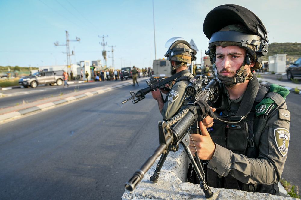 Israeli soldiers and police inspect the scene of shooting attack in Tapuah Junction, south of the West Bank city of Nablus, on May 2, 2021.