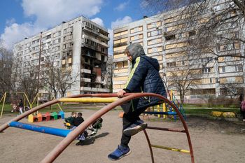 Children play on a playground in front of missile-damaged buildings in Zaporizhzhia, Ukraine.