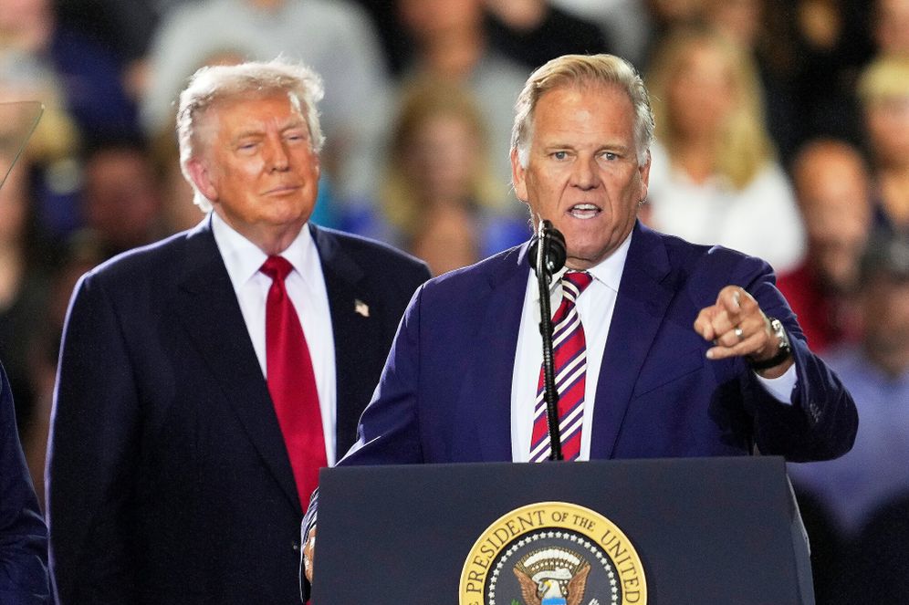 President Donald Trump listens to Republican Senate candidate Mike Rogers speak during an event at the General Motors Proving Ground Monday, July 27, 2026, in Milford, Mich.