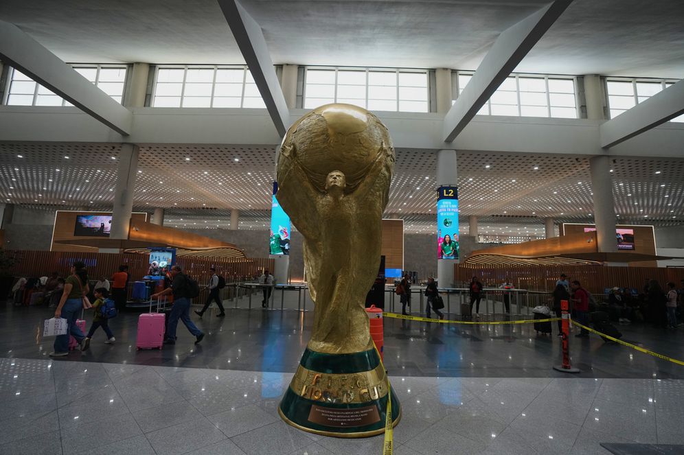 AP Photo/Fernando Llano يمر المسافرون بجوار تمثال لكأس العالم خلال جولة إعلامية مصحوبة بمرشدين لأعمال التجديد في مطار بينيتو خواريز الدولي، استعداداً لكأس العالم 2026 في مكسيكو سيتي، يوم الثلاثاء 19 مايو 2026