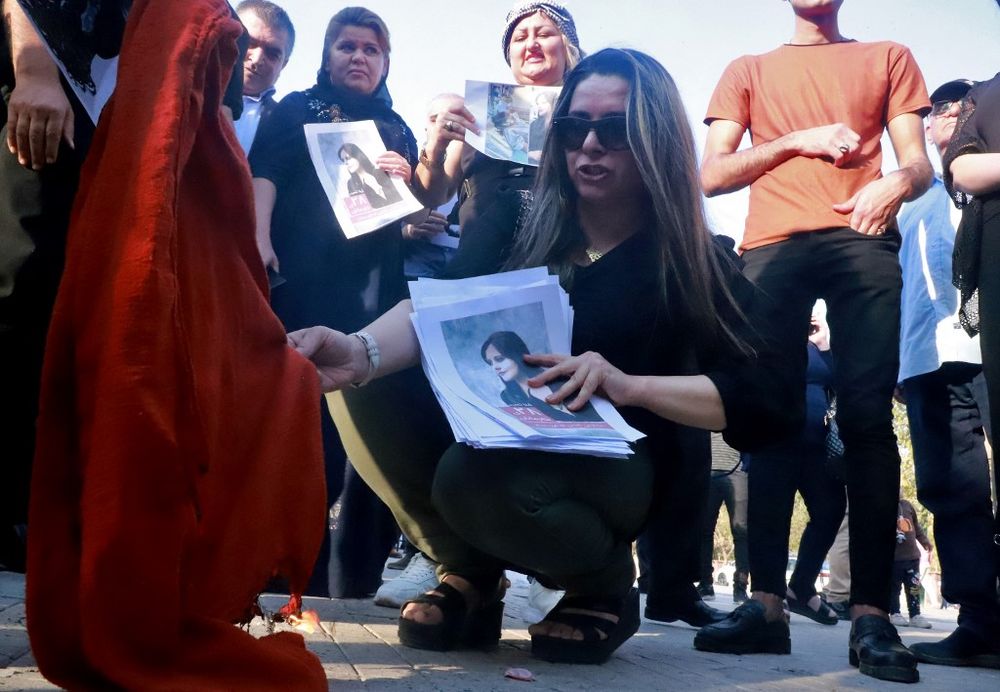 Iranian Kurds set a headscarf on fire during a march in the Iraqi Kurdish city of Sulaimaniya on September 19, 2022, against the killing of Mahsa Amini, a woman in Iran who died after being arrested by the Islamic republic's morality police.