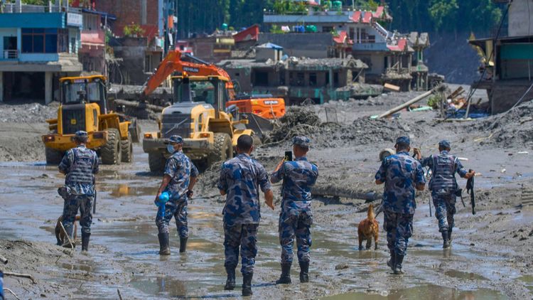 Des policiers népalais et des engins de terrassement en train de déblayer les débris laissés par les inondations, au Népal, le 27 août 2026