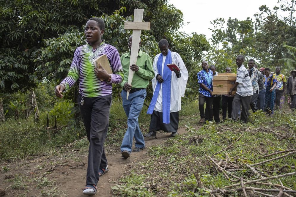 A pastor leads the funeral of Florence Masika and Zakayo Masereka during their burial rituals in Mpondwe, Uganda, after terrorists killed dozens of students in a school attack.