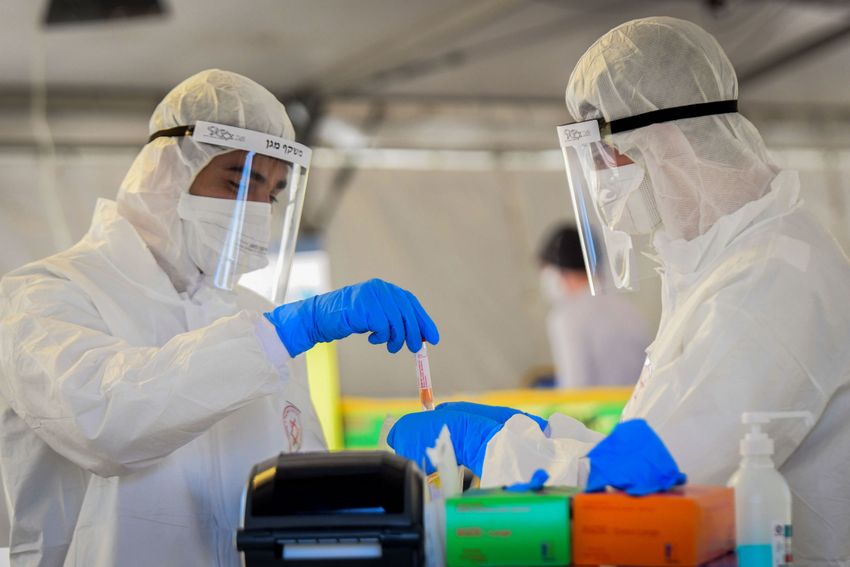 FILE - Magen David Adom medical team members handling a COVID-19 test sample at a drive-through coronavirus testing site in Tel Aviv, Israel. March 22, 2020.