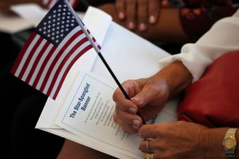 FILE - In this Aug. 16, 2019, file photo a citizen candidate holds an American flag and the words to The Star-Spangled Banner before the start of a naturalization ceremony at the US Citizenship and Immigration Services Miami field office