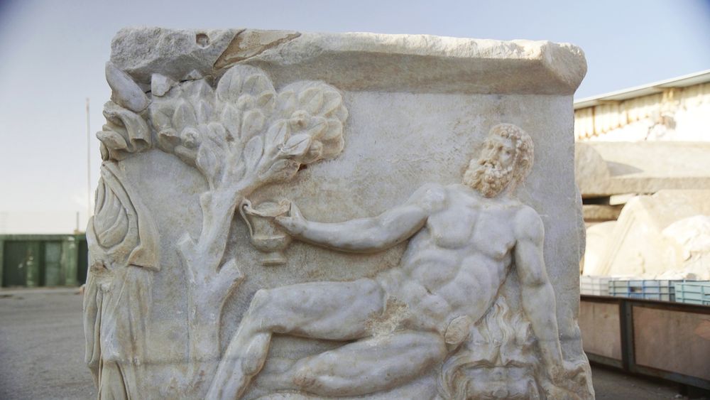 The side of the marble sarcophagus, depicting the scene of Hercules, sprawled on a lion's skin and holding a cup in his hand.