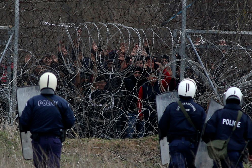 Greek riot police stand guard as migrants are held next to a barbedwire fence at the Greek-Turkish border in Kastanies on Wednesday, March 4, 2020.