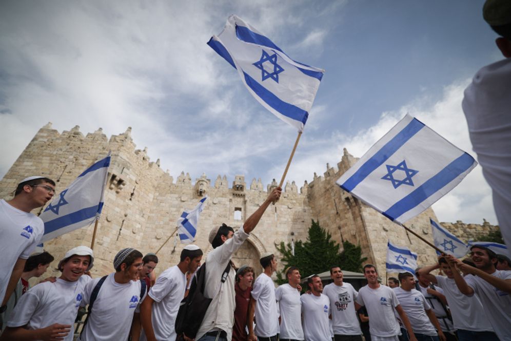 De jeunes hommes juifs tiennent des drapeaux israéliens à la porte de Damas dans la vieille ville de Jérusalem, le 18 mai 2023
