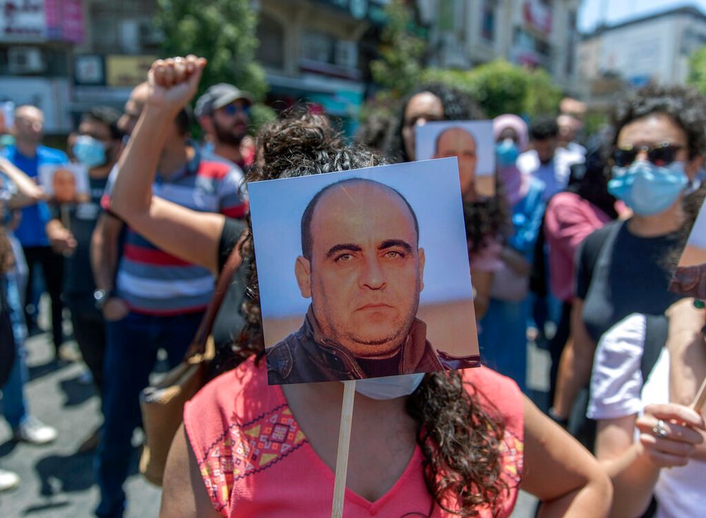 Des manifestants portent des photos de Nizar Banat, critique de l'AP, lors d'un rassemblement pour protester contre sa mort, à Ramallah, en Cisjordanie, le 24 juin 2021.