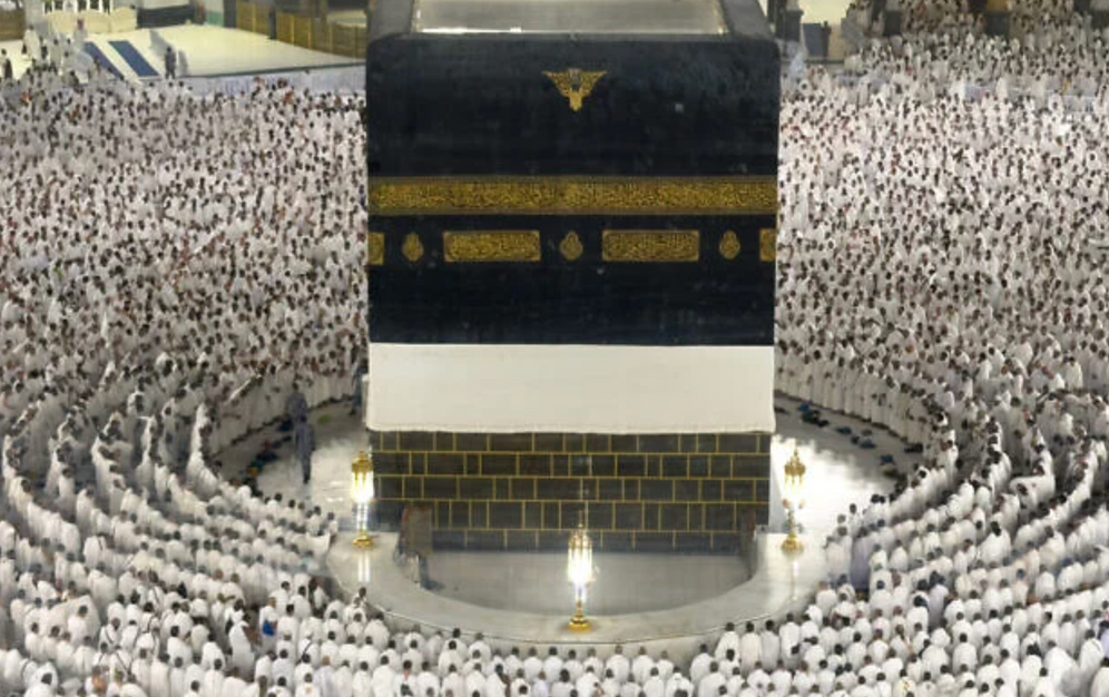 AP Photo/Altaf Qadri Sur cette photographie prise à travers une paroi vitrée, des pèlerins musulmans sont vus en train de prier autour de la Kaaba, le lieu le plus sacré de l’islam, dans la Grande Mosquée de La Mecque, en Arabie saoudite, lors du pèlerinage annuel du hajj, le 22 mai 2026.