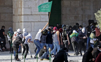 Des Palestiniens, dont l'un brandit un drapeau du Hamas, se heurtent à la police israélienne sur le Mont du Temple à Jérusalem, le 22 avril 2022.