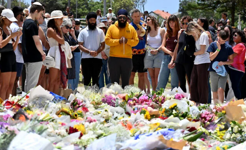 Des personnes en deuil se rassemblent devant des hommages floraux au Bondi Pavillion en mémoire des victimes d'une fusillade terroriste meurtrière visant un événement de Hanouka à Bondi Beach, à Sydney, le 15 décembre 2025.