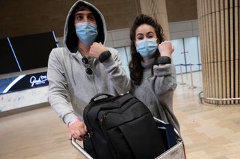 Israeli travelers hold up electronic monitoring bracelets they are required to wear after returning from abroad at the Ben Gurion airport near Tel Aviv, Israel, on March 1, 2021.