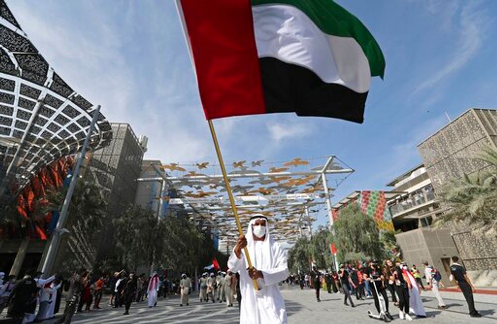 A man wearing a mask waves the national flag in Dubai, United Arab Emirates, December 2, 2021.