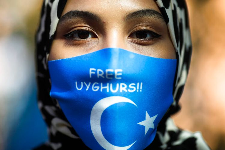 A woman wears a face mask reading 'Free Uyghurs' as she attends a protest during the visit of Chinese Foreign Minister Wang Yi in Berlin, Germany, September 1, 2020.
