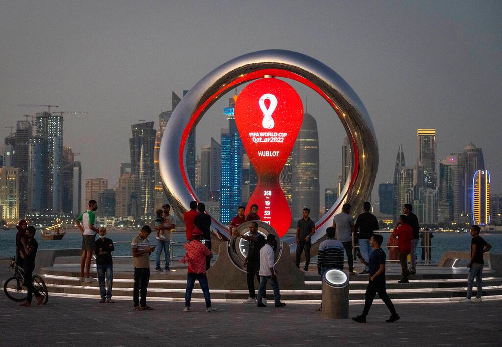 People gather around the official countdown clock showing the remaining time until the kick-off of the World Cup 2022, in Doha, Qatar.