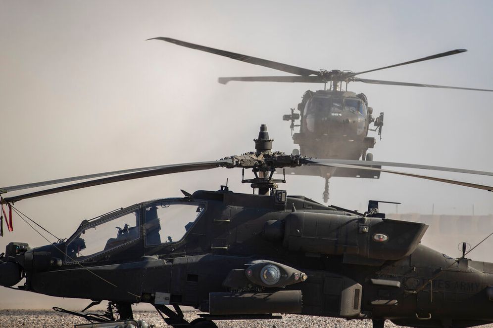AP Photo/Darko Bandic A Blackhawk helicopter lands next to an Apache attack helicopter at a US military base at an undisclosed location in the Middle East