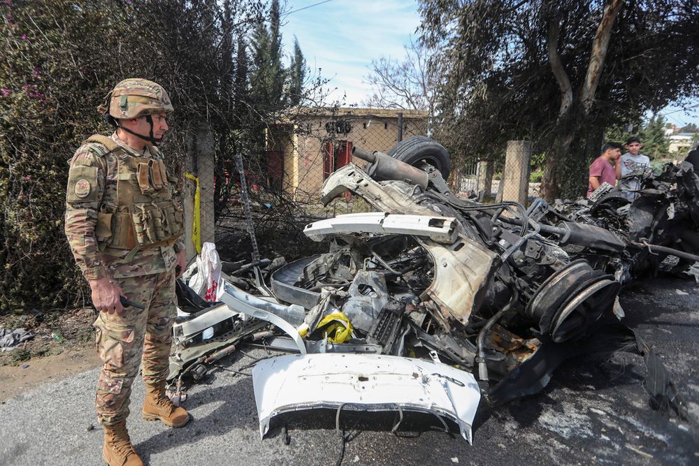 A Lebanese army officer stands next to a destroyed car in the southern outskirts of Tyre, Lebanon.