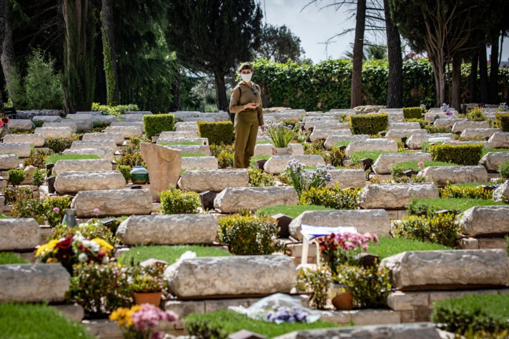 An Israeli soldier stands among the graves at the Mount Herzl Military Cemetery in Jerusalem on April 26, 2020.