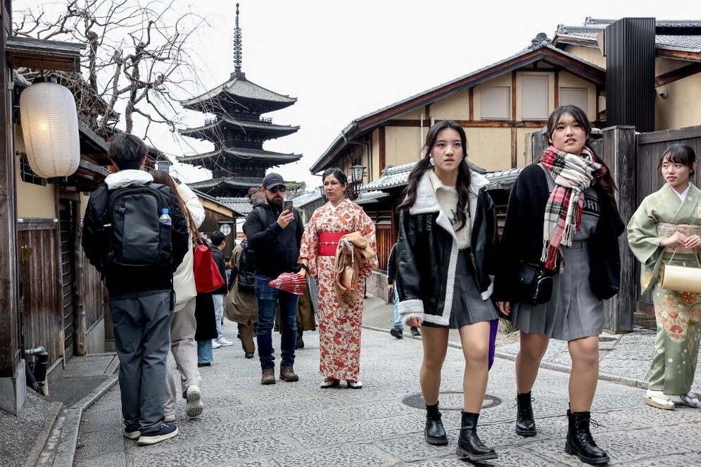 Tourists walk on the streets near Yasaka Pagoda (back) during a city tour in Kyoto, January 13, 2025.