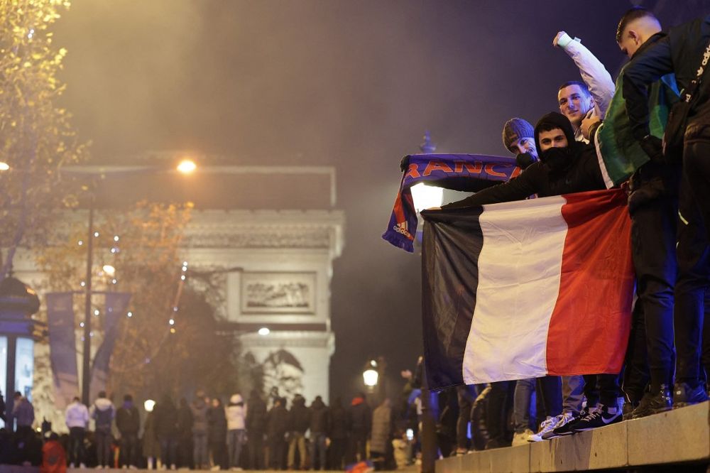 Soccer fans, next to the Arc de Triomphe, celebrate after France's victory over Morocco in the Qatar 2022 World Cup semi-final, on the Champs-Elysees in Paris on December 14, 2022.